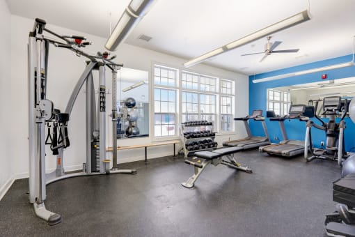 a gym with weights and cardio equipment and windows