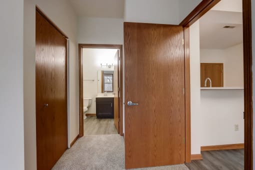 a bedroom with a closet and a bathroom with a sink and a mirror