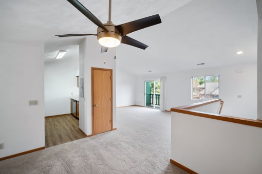 a living room with white walls and a ceiling fan