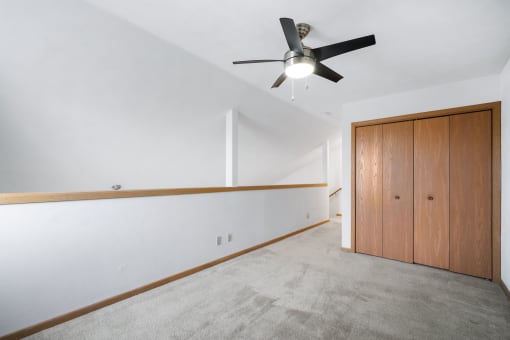 a living room with white walls and a ceiling fan