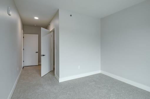A room with a carpeted floor and two doors.
