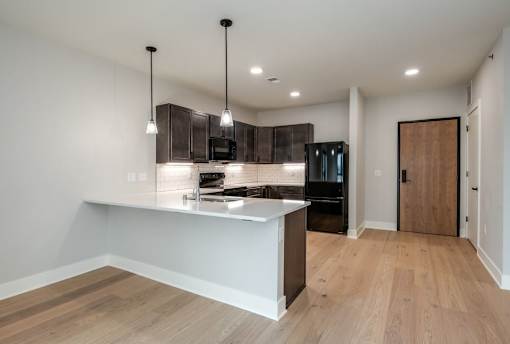 A modern kitchen with a wooden floor and a white countertop.