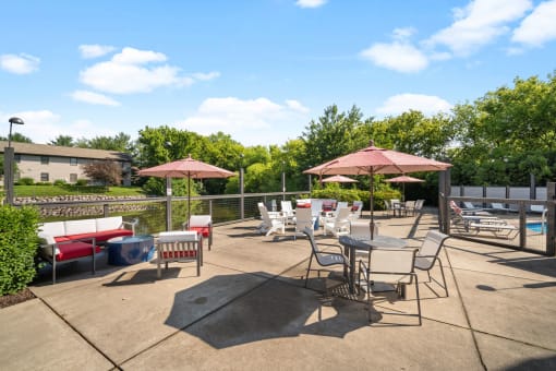 a patio with tables chairs and umbrellas and a pool