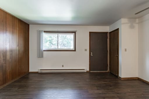 an empty living room with wood floors and a window