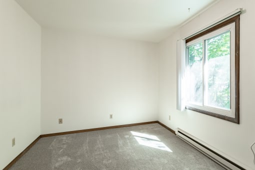 an empty room with a large window and carpet