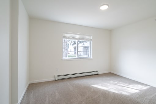 a bedroom with white walls and a window