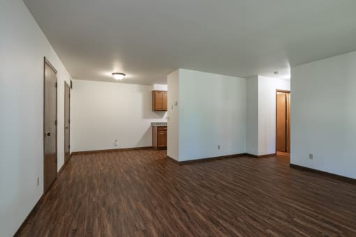 an empty living room with wood flooring and white walls