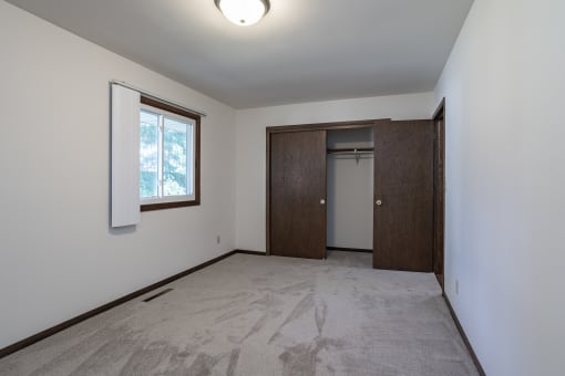 an empty living room with a door to a closet and a window