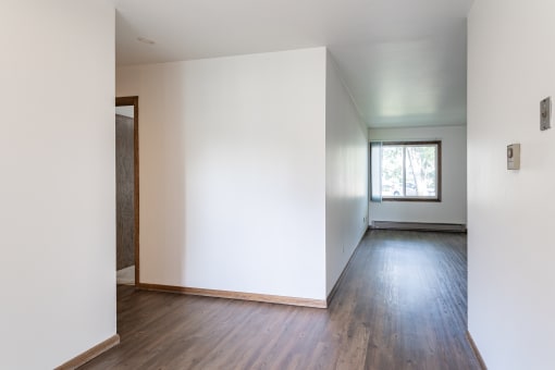 a room with white walls and wooden floors and a window
