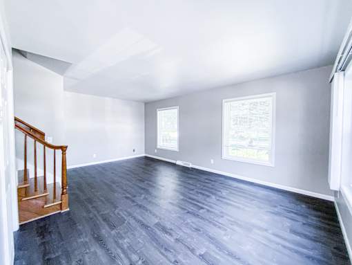 A room with a wooden staircase and grey flooring.