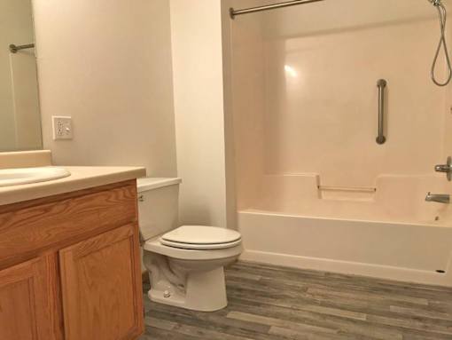 A white toilet sits next to a white bathtub in a bathroom.