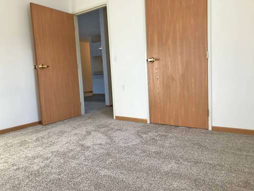 A room with two doors and a carpeted floor.