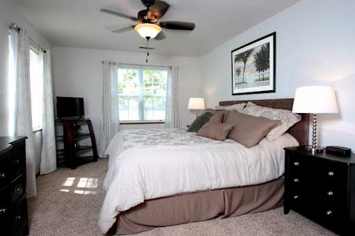 A bedroom with a bed, nightstand, and window.