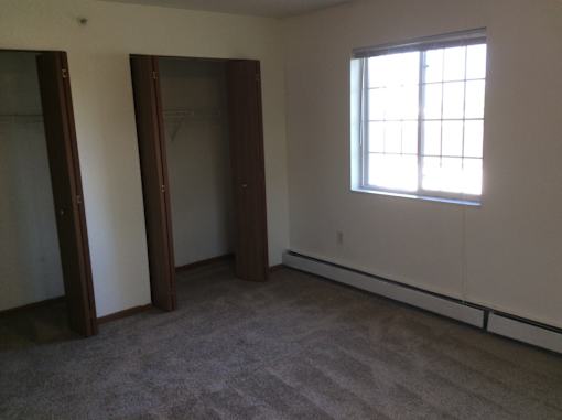 A room with a carpeted floor, a window, and a door.