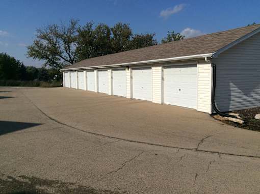 A large garage with white doors is situated in a parking lot.