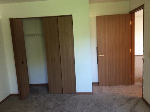 A room with a brown door and two brown wardrobes.