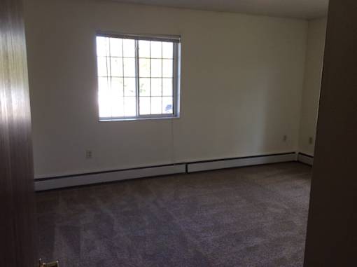 A room with a window and carpeted floor.