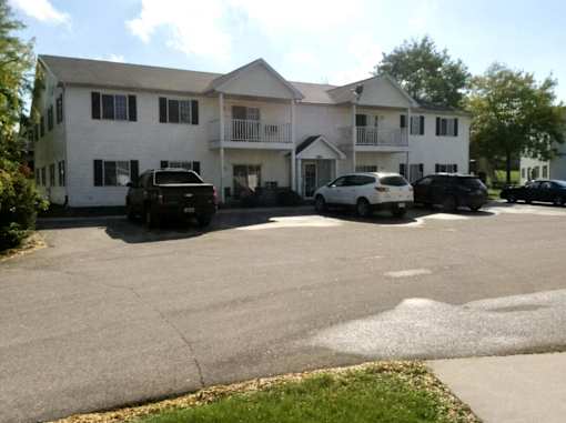 A white two story building with a black truck and car parked in front.