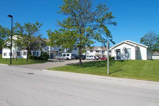 A street view of a residential area with houses and parked cars.