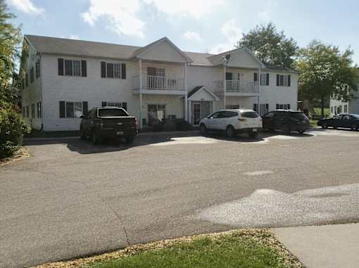 A white two-story building with a black car parked in front.