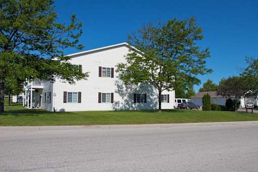 A white building with a green tree in front.