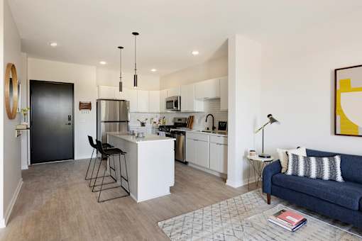 A modern kitchen with a bar stool and a blue sofa.