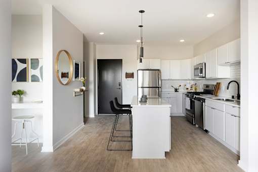 A modern kitchen with white cabinets and a black door.