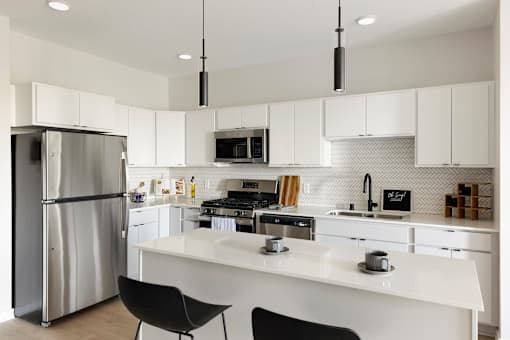 A modern kitchen with white cabinets and a stainless steel refrigerator.