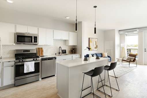 A modern kitchen with a white island and bar stools.