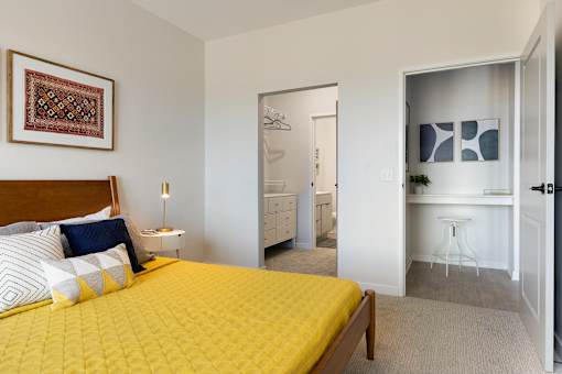 A bedroom with a yellow bedspread and a white dresser.