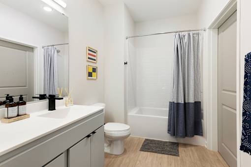 A bathroom with a white sink, toilet, and grey shower curtain.