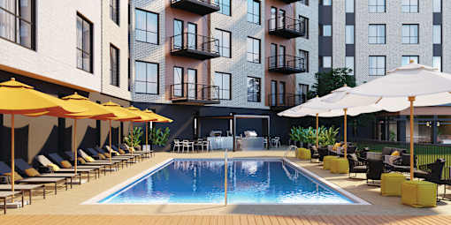 A pool surrounded by lounge chairs and umbrellas in front of a building.