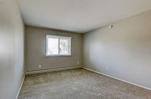 A room with a window and carpeted floor.