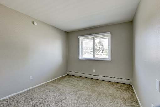 A room with a window and carpeted floor.