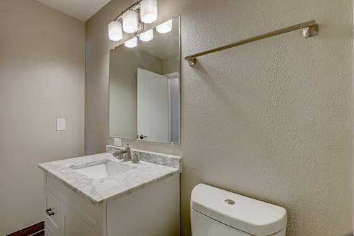 A bathroom with a sink, toilet and mirror.