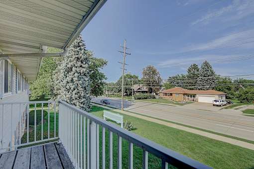 A view from a porch looking out at a street with houses and trees.