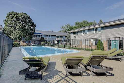 A pool with sun loungers in front of a building.