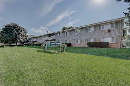 A sunny day at the apartment complex with a green lawn in front.