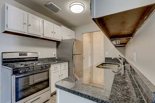 A kitchen with a stove, refrigerator, and cabinets.