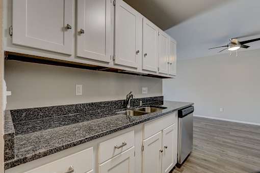 A kitchen with white cabinets and a black countertop.
