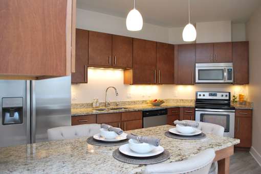 A kitchen with a granite countertop and a stainless steel refrigerator.