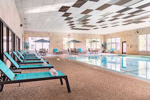 A large indoor swimming pool with lounge chairs and umbrellas.