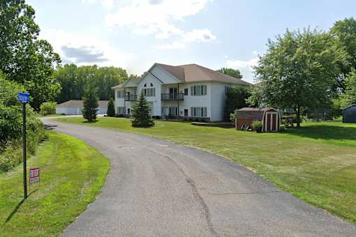 A road leading to a large white house with a red roof.