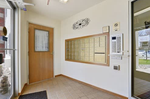 A hallway with a wooden door and a wall-mounted thermostat.