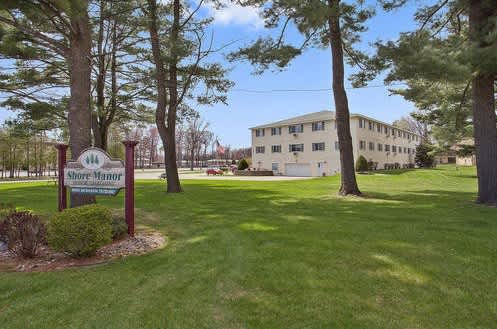 A sign that says "Shore Manor" stands in front of a building.