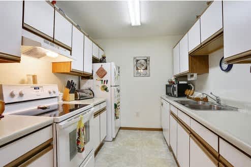 A kitchen with white appliances and white cabinets.