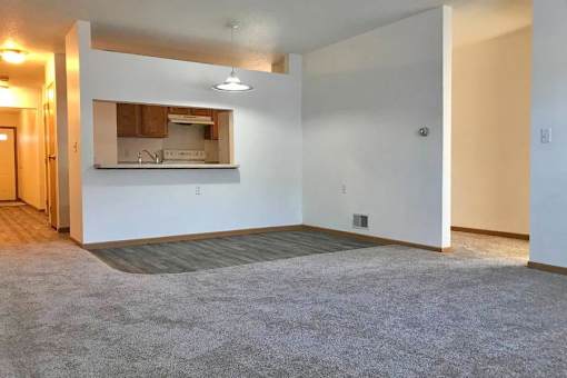 A spacious living room with a kitchenette in the background.