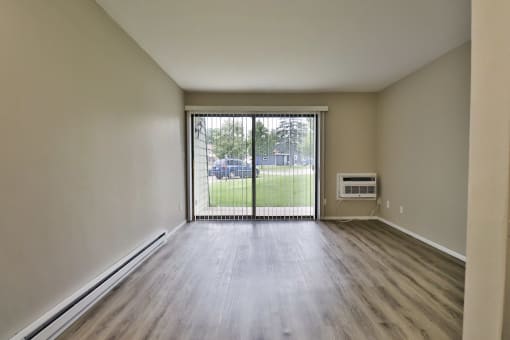 an empty living room with a sliding glass door to a yard