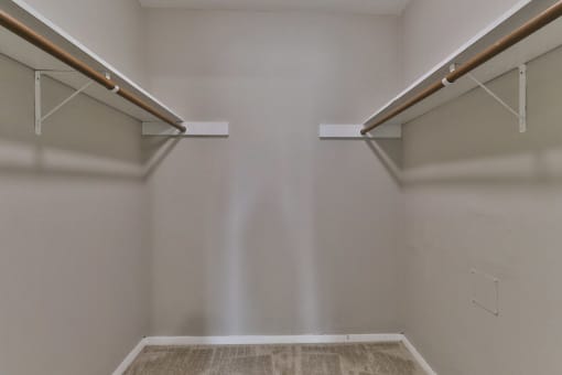a walk in closet with two shelves and two hanging racks on the wall