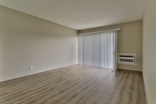an empty living room with blinds and a window